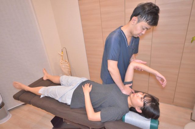 バネ指と関連する肩まわりの緊張を整えるために施術している様子
